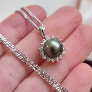 18ct White Gold Black Pearl and Diamond Cluster Pendant in hand