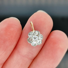 Load image into Gallery viewer, A flower shaped diamond cluster pendant in yellow gold and platinum, held in a hand
