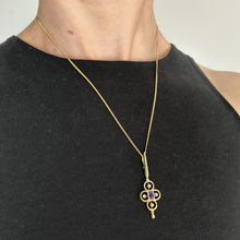 Load image into Gallery viewer, A yellow gold pendant with an oval amethyst and four white seed pearls, with a curb chain, modelled by a woman wearing a black top
