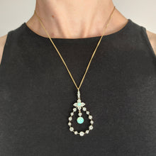 Load image into Gallery viewer, A pear shaped open pendant set with opals and diamonds, in gold and silver, with a gold chain, modelled by a woman wearing a black top
