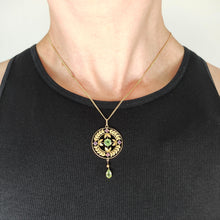 Load image into Gallery viewer, A peridot and amethyst yellow gold drop pendant, with a chain, modelled by a woman wearing a black top
