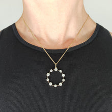 Load image into Gallery viewer, A ten stone old cut diamond open circle pendant in silver and gold, with a gold chain, modelled by a woman wearing a black top
