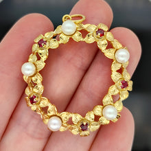 Load image into Gallery viewer, A yellow gold ruby and pearl flower open circle pendant, held in a hand
