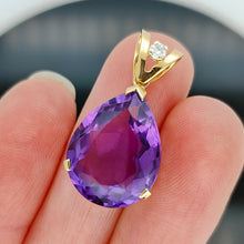 Load image into Gallery viewer, A pear shaped amethyst pendant with a single diamond in yellow gold, held in a hand
