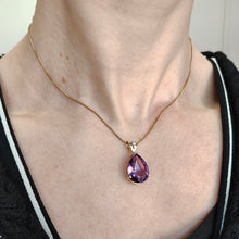 Load image into Gallery viewer, A pear shaped amethyst pendant with a single diamond in yellow gold, modelled around a neck with a gold chain
