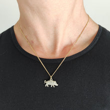 Load image into Gallery viewer, A diamond and ruby set silver pig charm with a gold jump ring, with a gold chain, modelled by a woman wearing a black top
