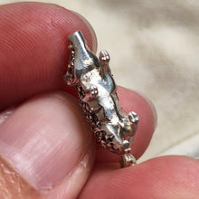 Load image into Gallery viewer, A diamond and ruby set silver pig charm with a gold jump ring, held in a hand
