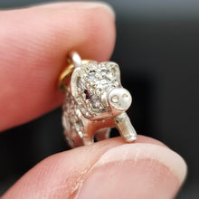Load image into Gallery viewer, A diamond and ruby set silver pig charm with a gold jump ring, held in a hand
