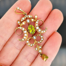 Load image into Gallery viewer, A peridot and pearl Art Nouveau style pendant in yellow gold, held in a hand
