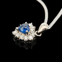Load image into Gallery viewer, A heart shaped sapphire and diamond cluster pendant, with a curb link chain, on a black background
