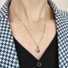 Load image into Gallery viewer, A heart shaped sapphire and diamond cluster pendant, with a curb link chain, modelled by a woman
