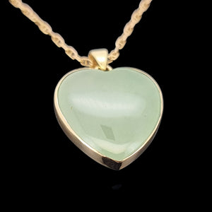 Heart-shaped green jade pendant with gold frame on a black background