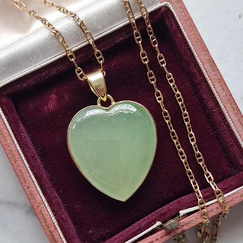 Heart-shaped green jade pendant on a gold chain in an antique jewellery box