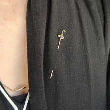 Load image into Gallery viewer, A sapphire and pearl tie pin in yellow gold, modelled on a black cardigan
