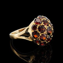 Load image into Gallery viewer, A round garnet domed cluster ring in yellow gold, against a black background
