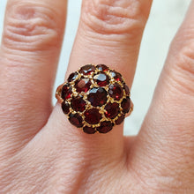 Load image into Gallery viewer, A round garnet domed cluster ring in yellow gold, modelled on a middle finger
