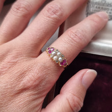 Load image into Gallery viewer, Close-up of a hand wearing a ring with pearls, diamonds and rubies, with Harrods branding in the background
