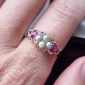 Gold ring with pearls, diamonds and rubies on a finger