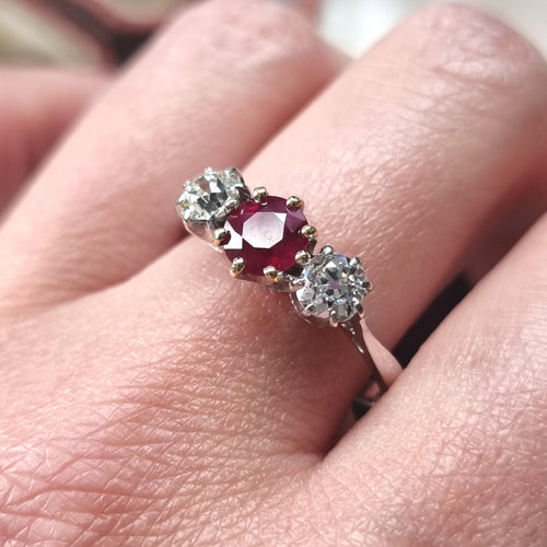 Ring with a ruby and two diamonds modelled on a finger