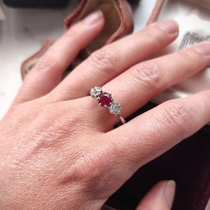 A ruby and diamond three stone ring modelled on a finger