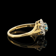 Load image into Gallery viewer, A blue zircon and diamond flower cluster ring in yellow and white gold, on a black background
