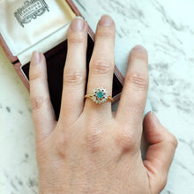Load image into Gallery viewer, A blue zircon and diamond flower cluster ring in yellow and white gold, modelled on a hand
