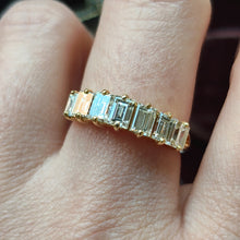Load image into Gallery viewer, A seven stone baguette cut diamond graduated ring in yellow gold, modelled on a hand
