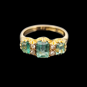 Gold ring with emerald and diamond accents on a black background