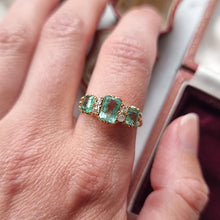 Load image into Gallery viewer, Gold ring with emerald and diamond stones modelled on a hand
