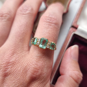 Gold ring with emerald and diamond stones modelled on a hand