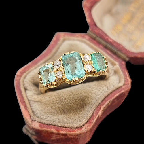 Gold ring with emerald and diamond stones in an antique ring box