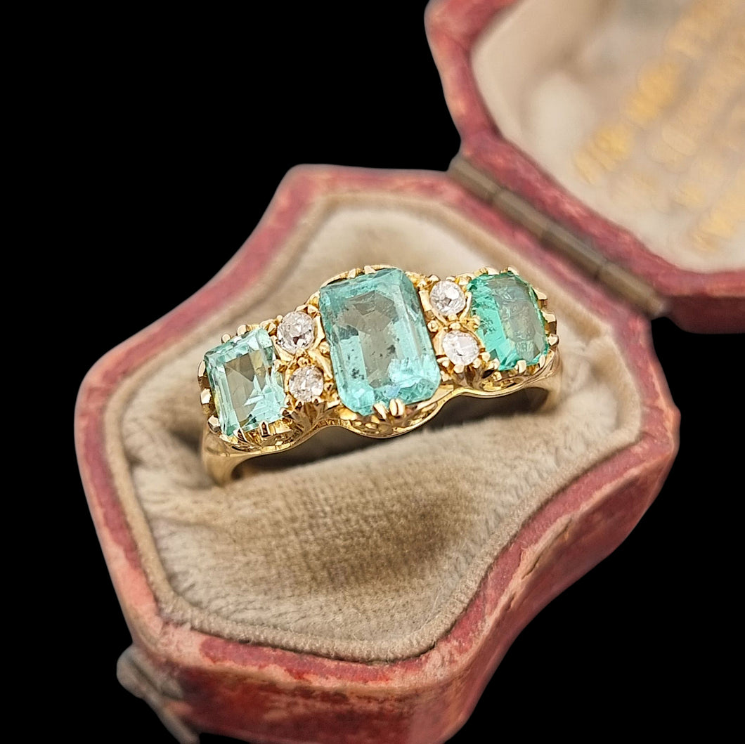 Gold ring with emerald and diamond stones in an antique ring box