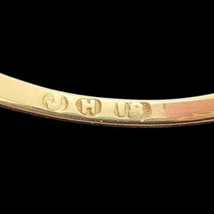Gold ring showing the maker's mark and 18 stamp inside the shank on a black background