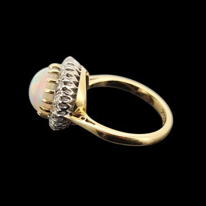 Gold ring with opal and diamond accents on a black background