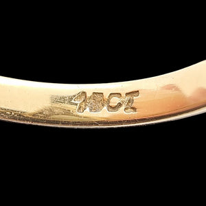 Gold ring with '18CT' marking in the shank on a black background