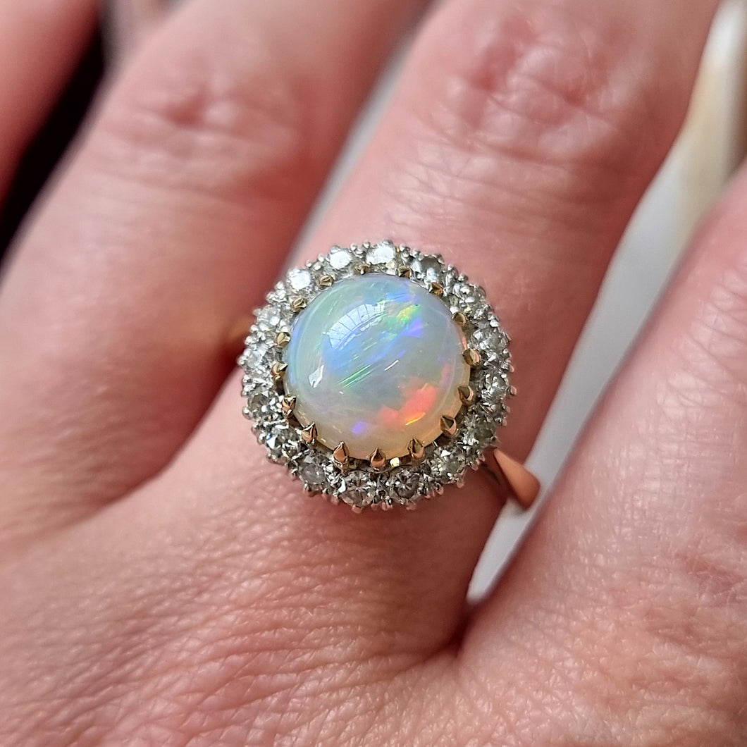 Ring with an opal stone and diamond halo on a finger