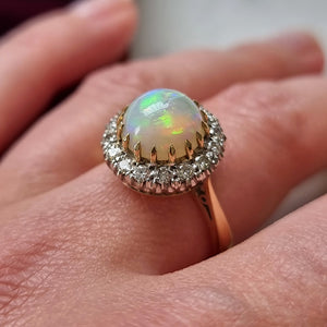 Ring with an opal stone and diamond accents on a finger