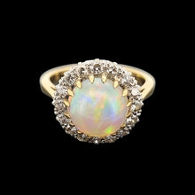 Load image into Gallery viewer, Gold ring with a large opal stone and smaller diamonds on a black background
