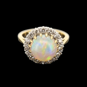Gold ring with a large opal stone and smaller diamonds on a black background