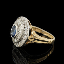 Load image into Gallery viewer, An oval sapphire and diamond cluster ring in yellow and white gold, on a black background
