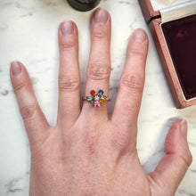 Load image into Gallery viewer, A multi-coloured gemstone flower shaped ring in white gold, modelled on the middle finger of a hand
