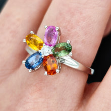Load image into Gallery viewer, A multi-coloured gemstone flower shaped ring in white gold, modelled on a hand
