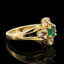 Load image into Gallery viewer, An emerald and diamond compass set cluster ring in yellow gold with split shoulders, with a black background

