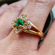 Load image into Gallery viewer, An emerald and diamond compass set cluster ring in yellow gold with split shoulders, modelled on a hand
