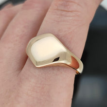 Load image into Gallery viewer, A gold hexagonal shaped signet ring, modelled on a hand
