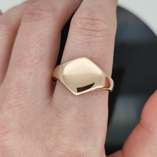 Load image into Gallery viewer, A gold hexagonal shaped signet ring, modelled on a hand
