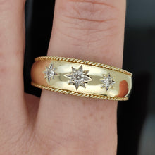 Load image into Gallery viewer, A three stone diamond star set gypsy ring in yellow gold, modelled on the index finger of a hand, on a black background
