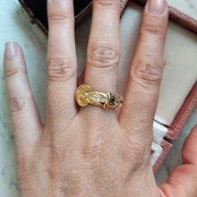 Load image into Gallery viewer, A yellow gold buckle band ring with two diamonds, modelled on a hand
