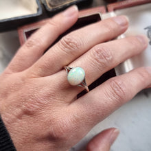 Load image into Gallery viewer, Hand wearing a ring with an opal on a neutral background
