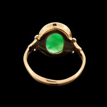 Load image into Gallery viewer, An oval shaped green jade ring in yellow gold, on a black background
